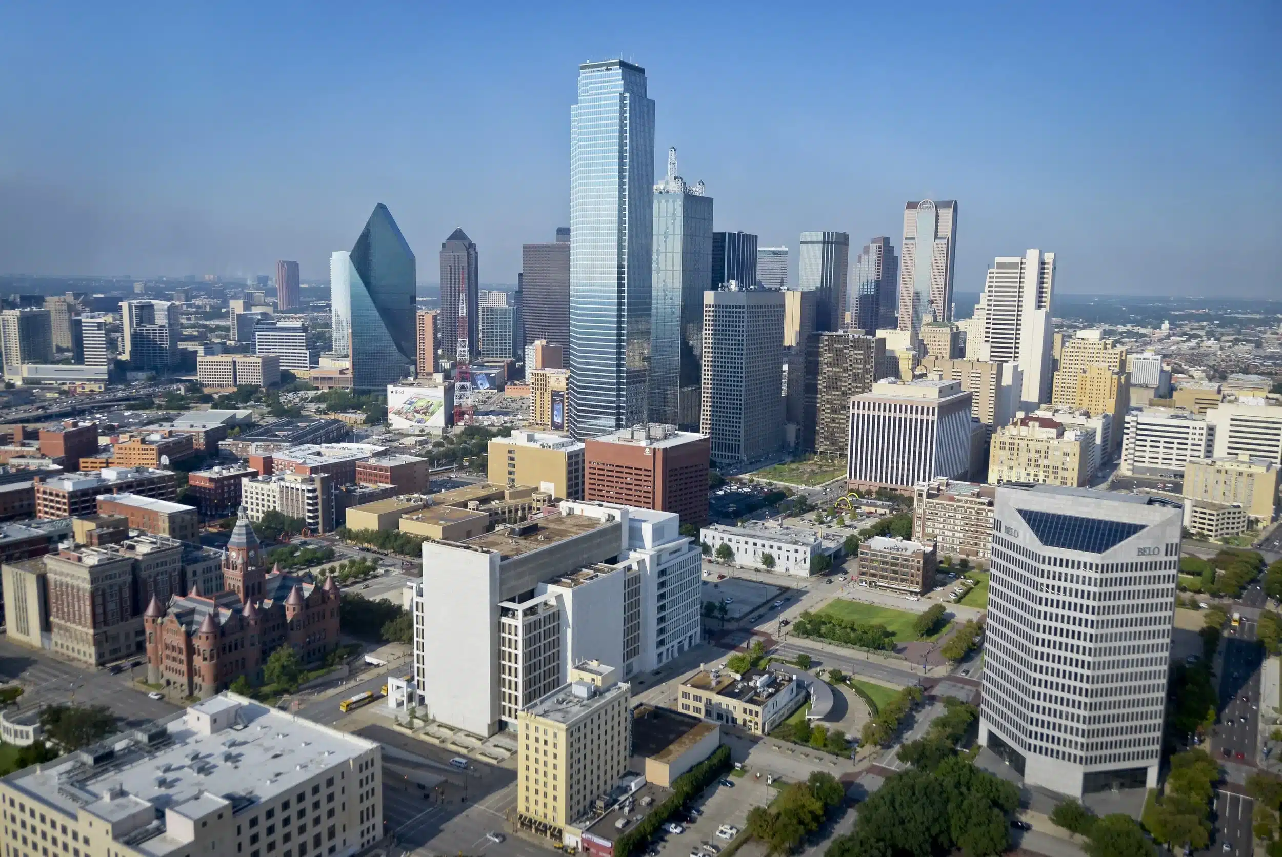 Aerial view of downtown Dallas, Texas, featuring modern skyscrapers, office buildings, and clear blue sky.